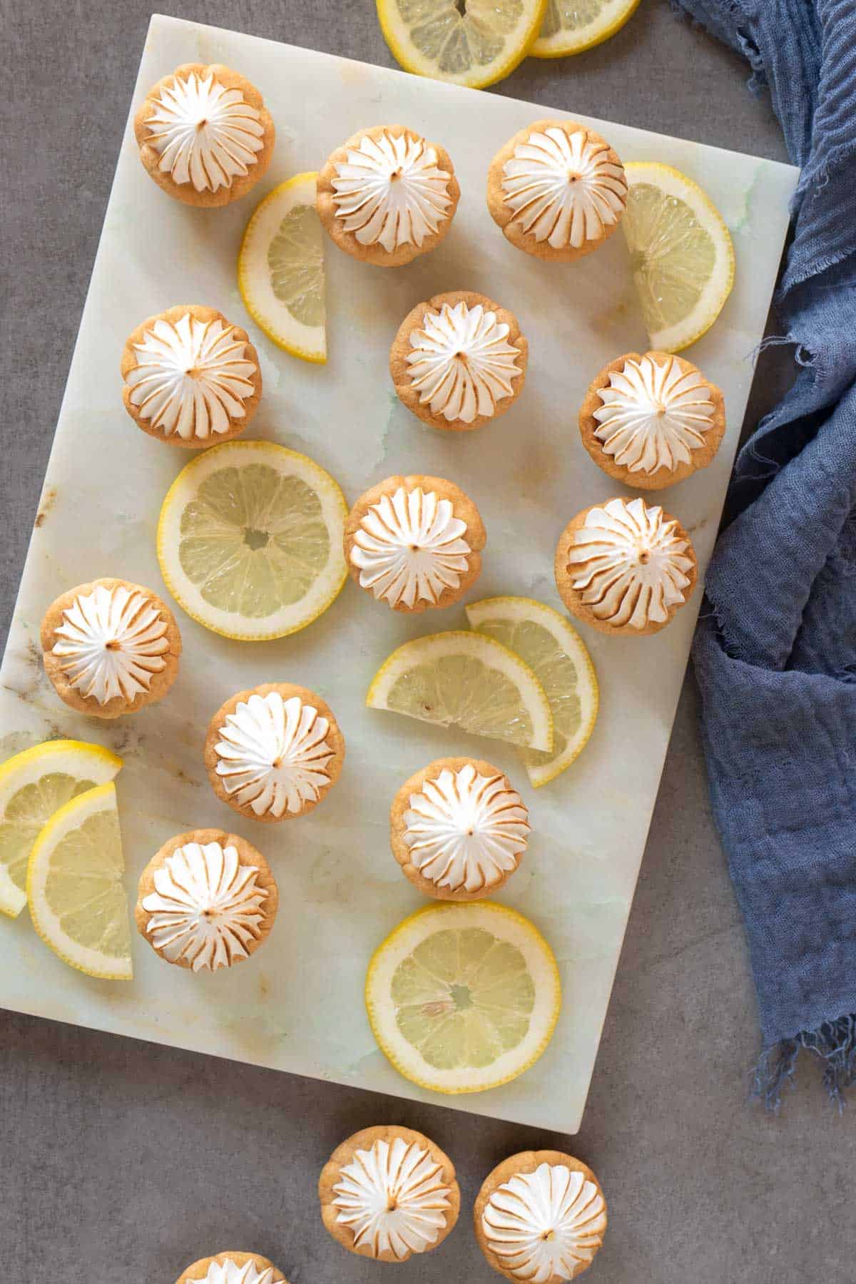 lemon meringue pie bites and lemon slices on a marble table