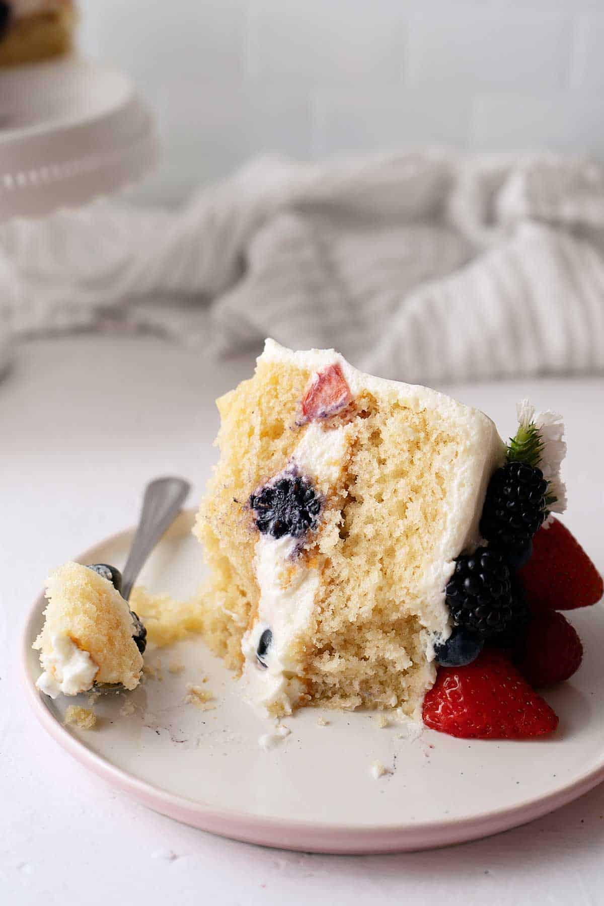 Half eaten portion of berry cake with white frosting