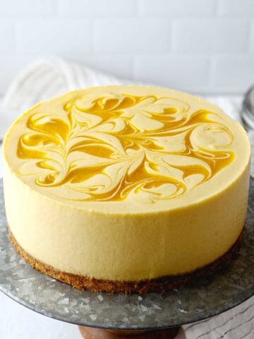 no-bake mango cheesecake on a cake stand