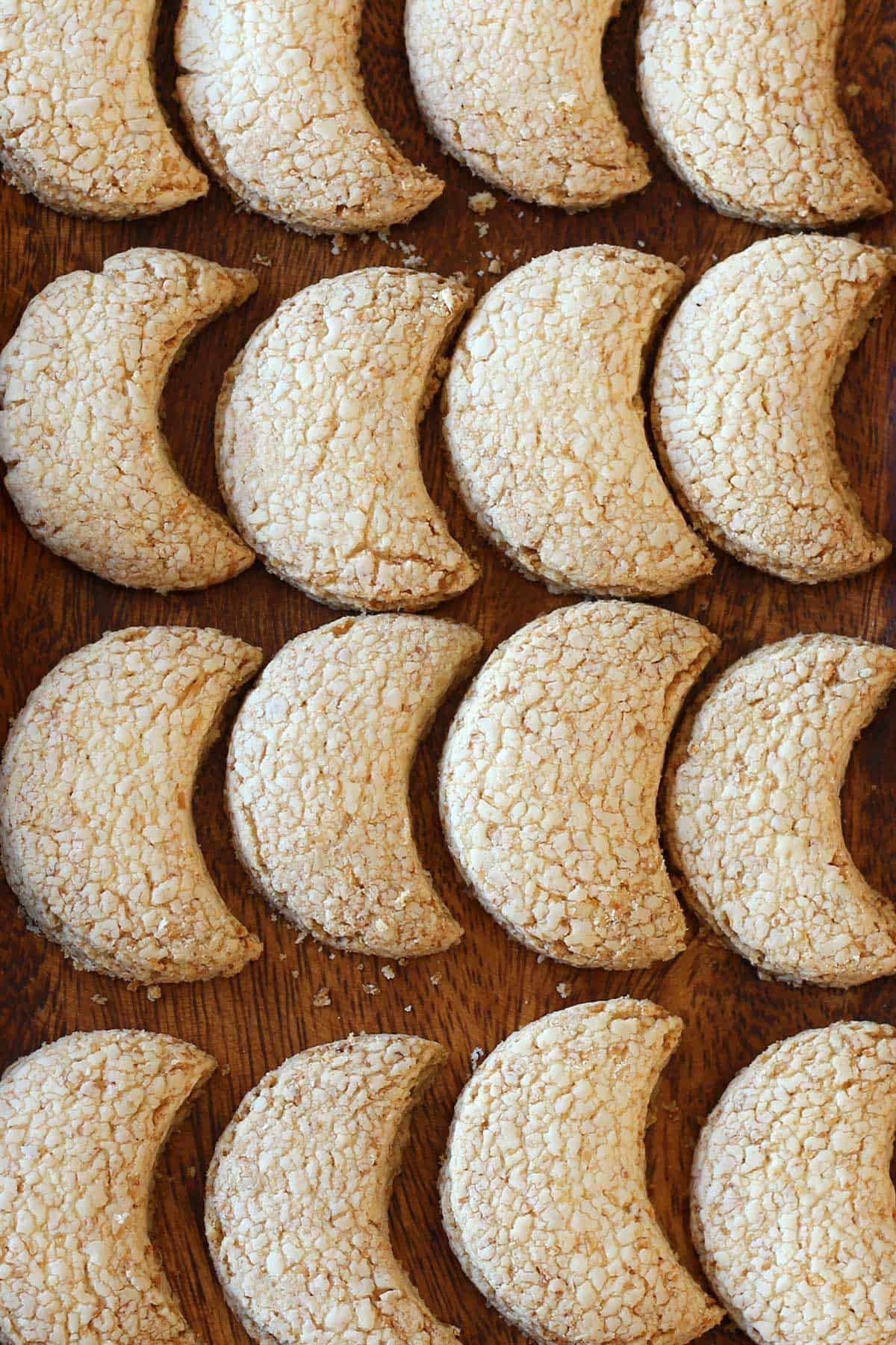 Halfmoon coconut cookies on a wooden tray.