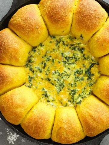 curry bread with cheese spinach dip in a cast iron skillet