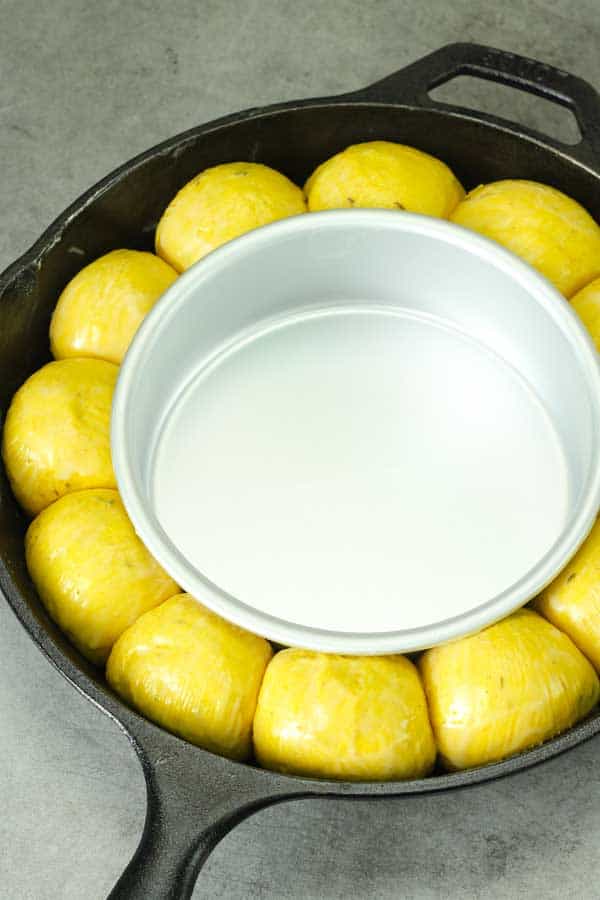 uncooked curry bread in a cast iron skillet with a smaller cake pan in the center