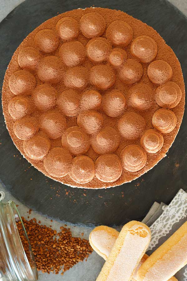 No bake tiramisu cheesecake from top with coffee granules and ladyfingers on the side