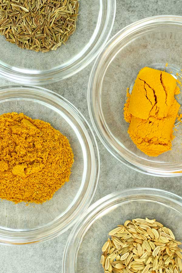 curry powder, turmeric powder, fennel seeds and cumin seeds in bowls