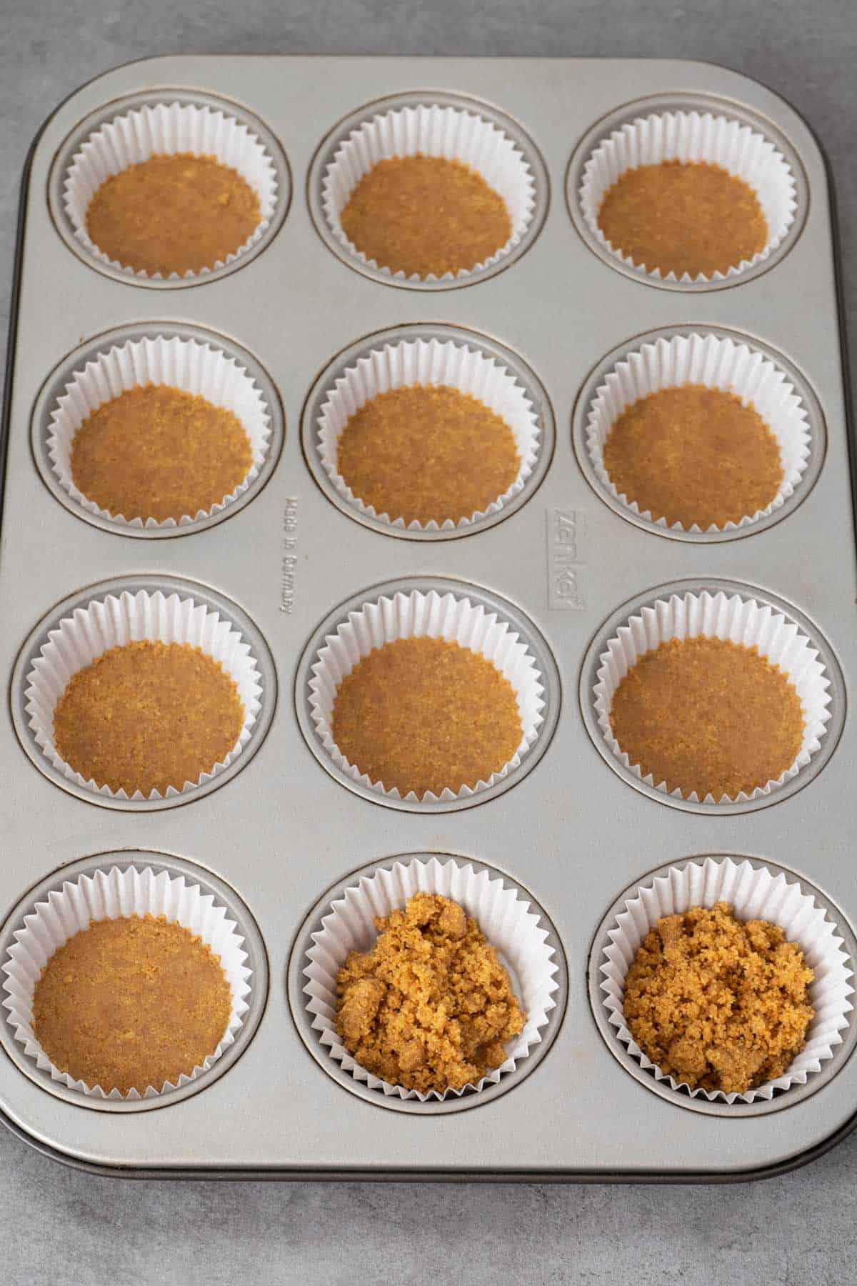 Mini cheesecakes crust base in a muffin tin