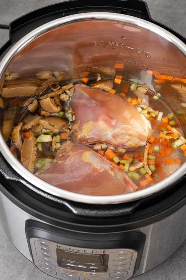 Instant pot with all ingredients for chicken congee