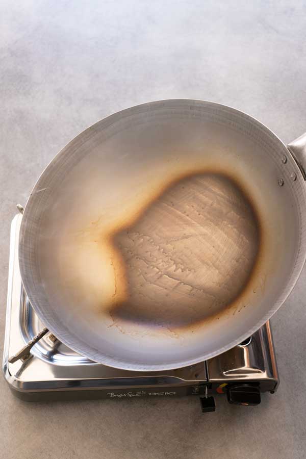 seasoning a carbon steel wok over a fire stove