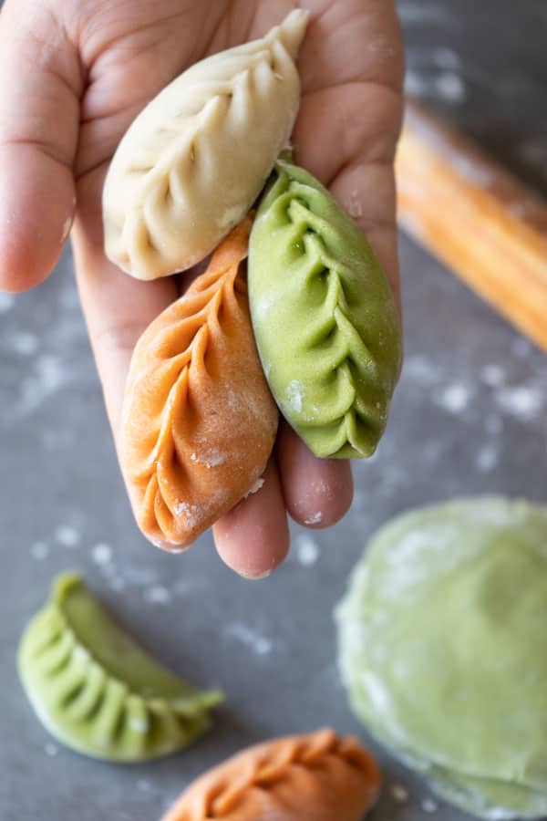 holding 3 colored raw dumplings