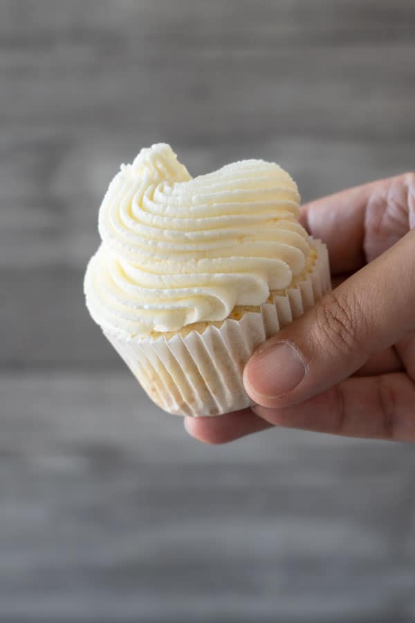 holding a cupcake with white frosting