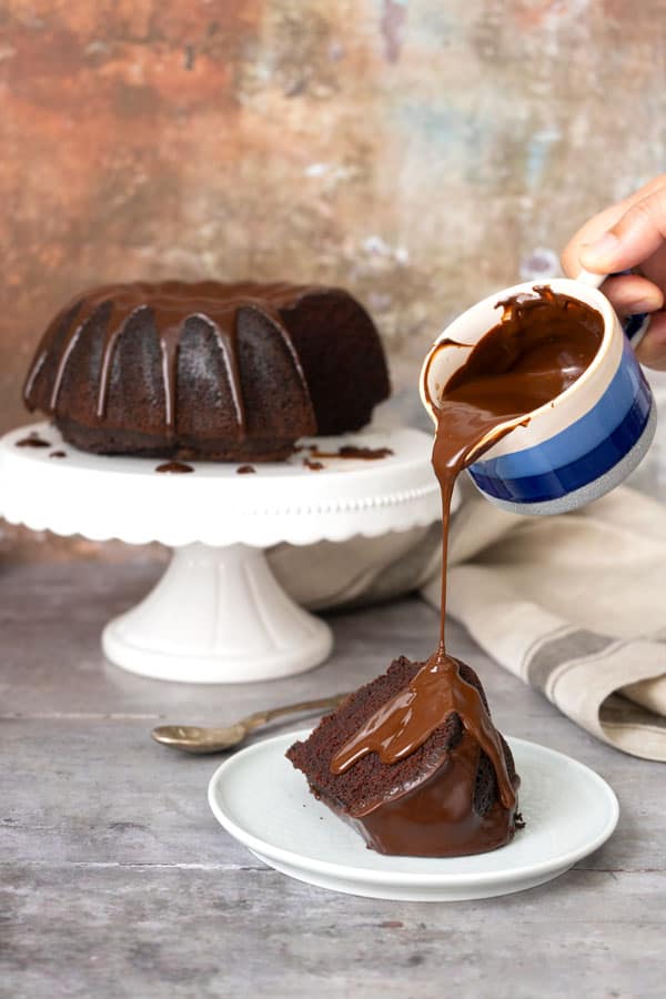 pouring chocolate sauce over chocolate cake portion