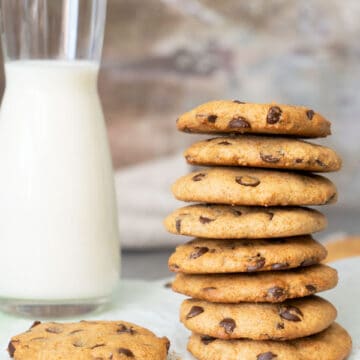 stacked chocolate chip cookies with a glass of milk