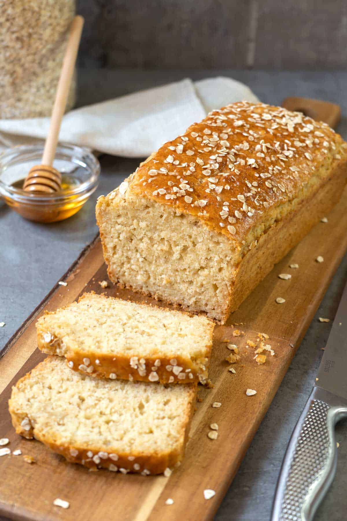 2 slices and a loaf of no yeast honey oat bread on a table