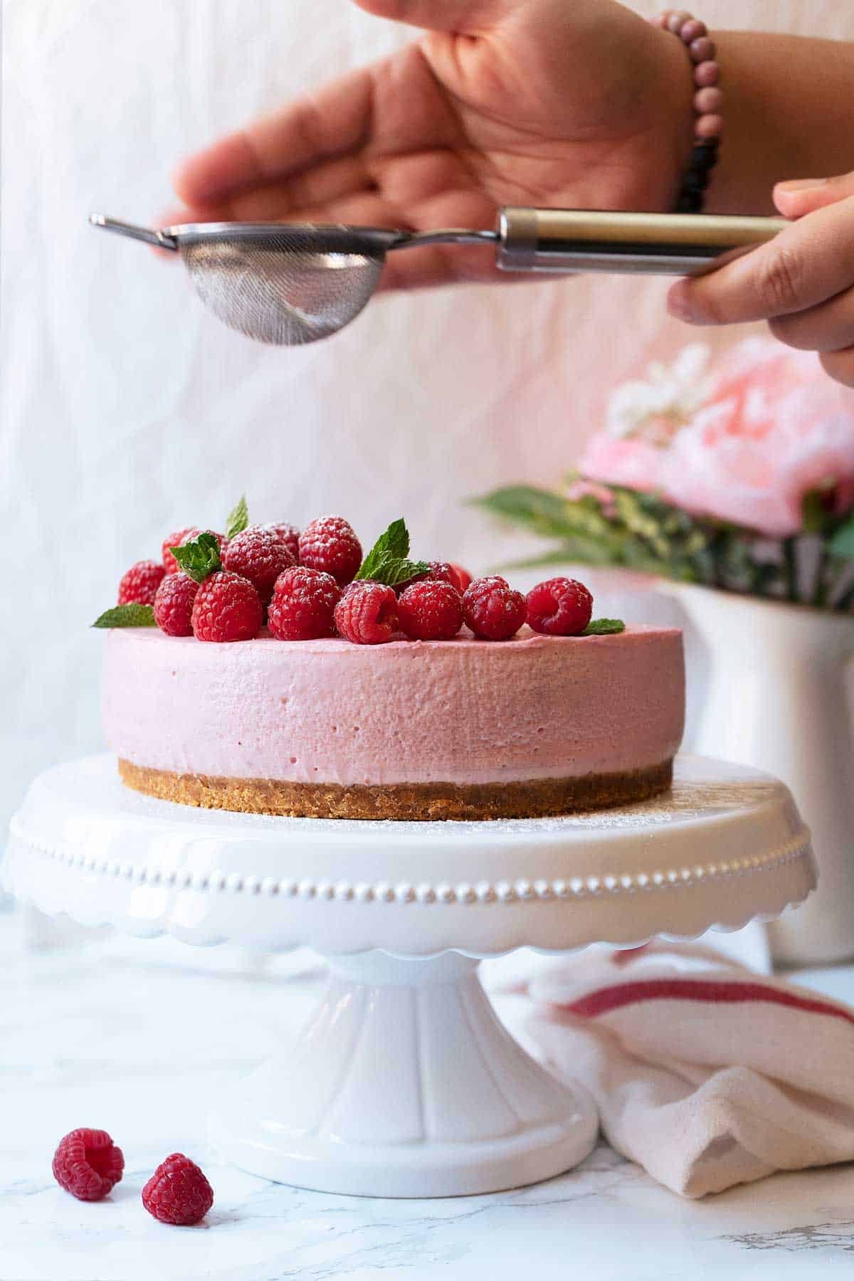 sugar dusting a no-bake raspberry cheesecake