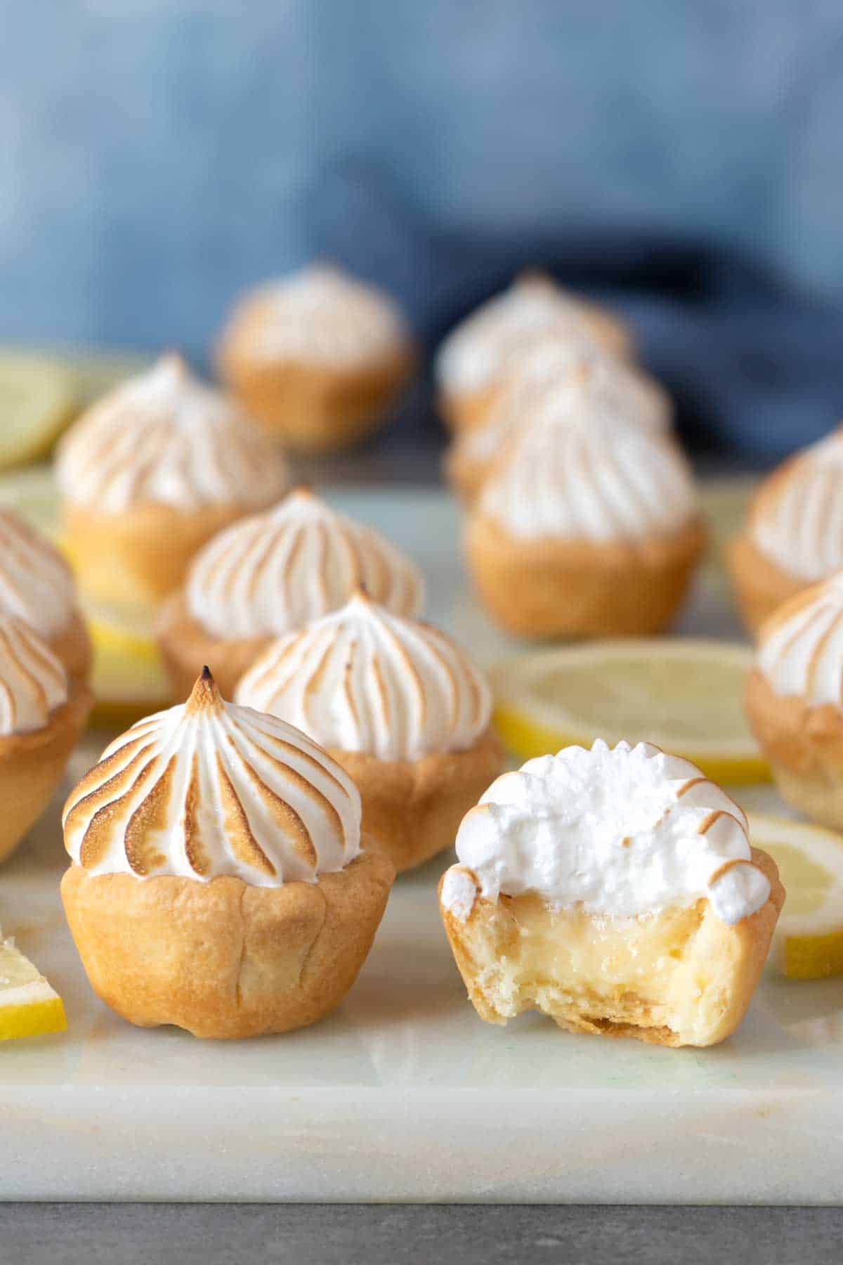 several lemon meringue pie bites on a table together with one half eaten