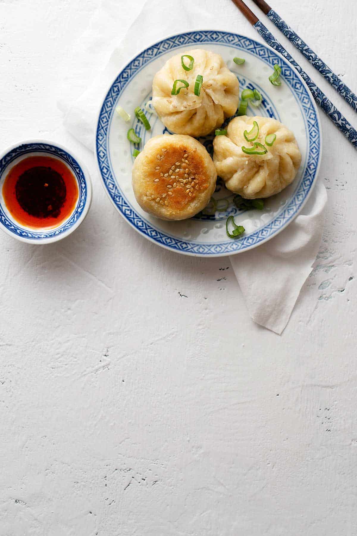 pan fried steamed buns with a chili oil bowl