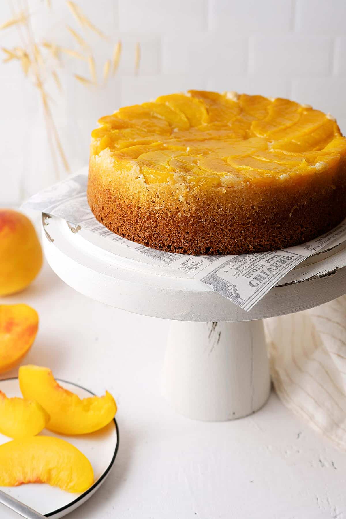 upside down peach cake on a white stand