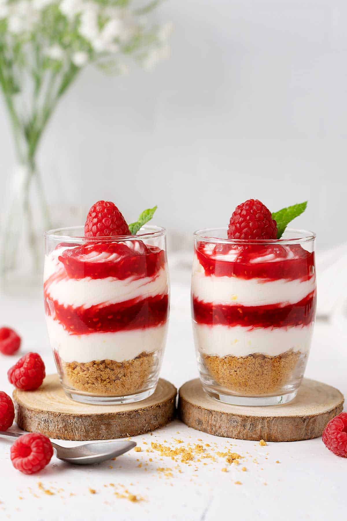 Two raspberry cheesecake shots on the table.