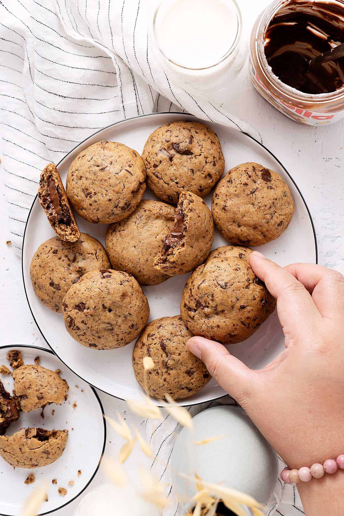 grabbing a Nutella stuffed chocolate chunk cookie from a plate