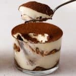 scooping tiramisu from a glass.