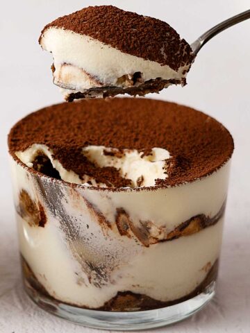 scooping tiramisu from a glass.