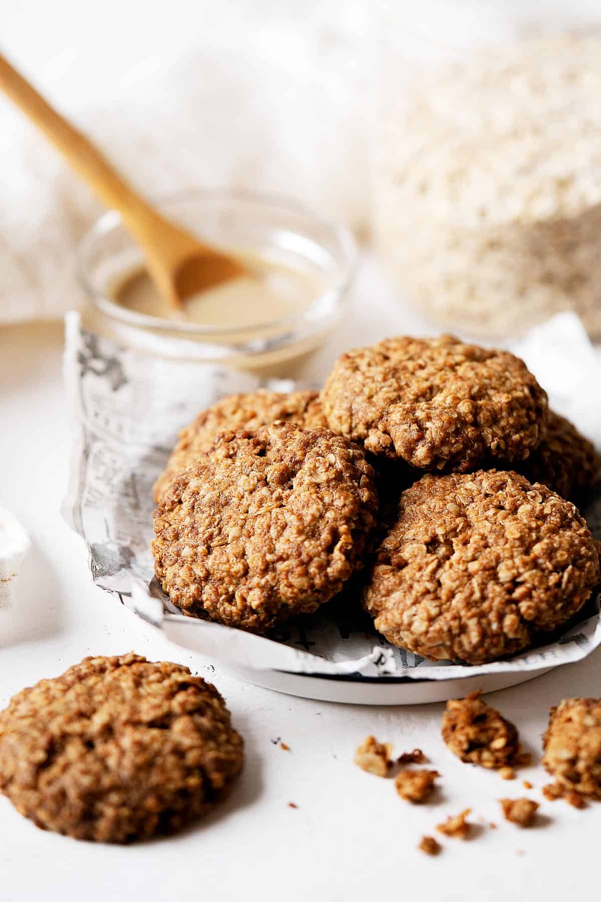 Some healthy tahini cookies on a plate with broken ones on the side