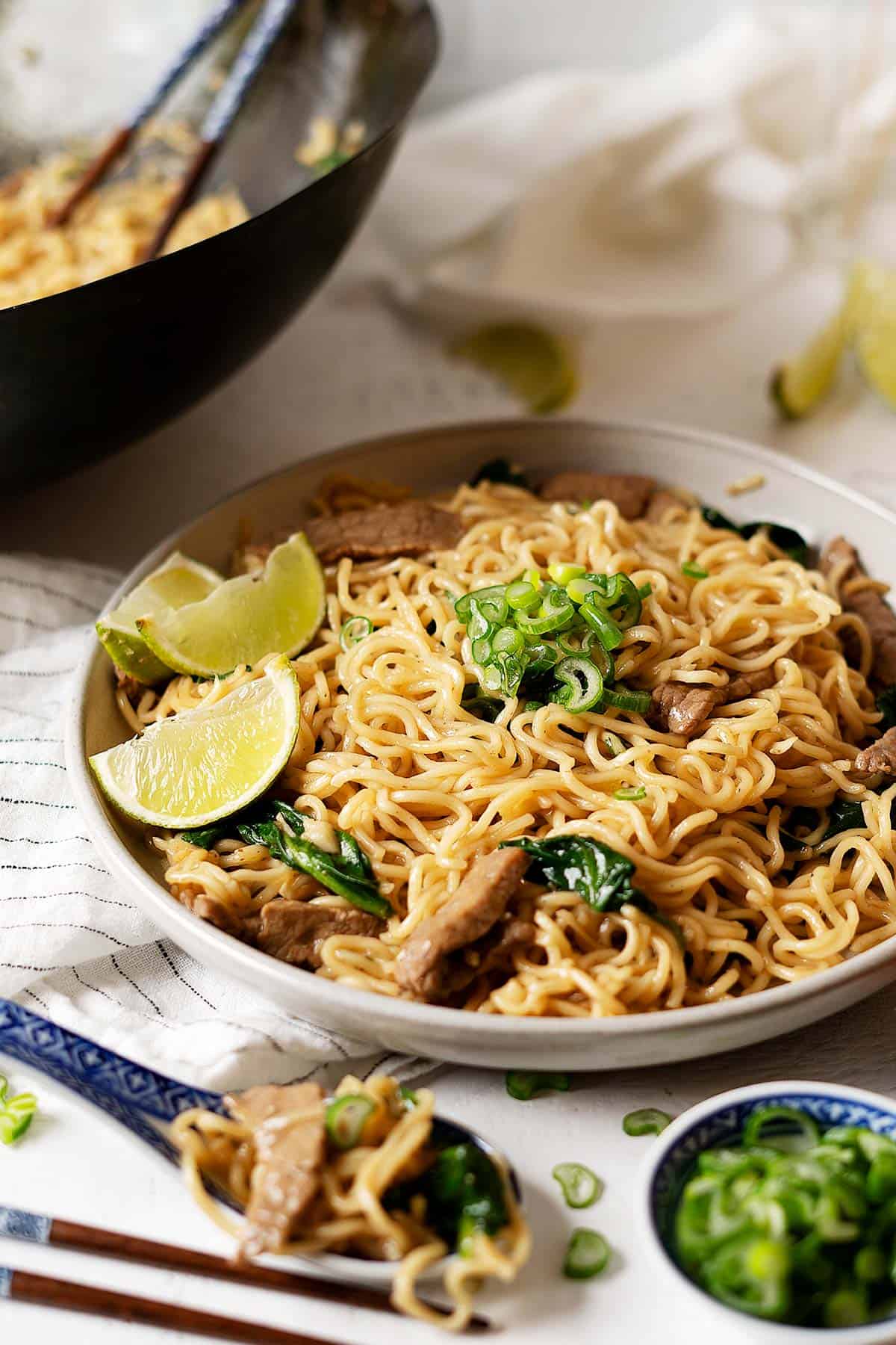 10 minute lo mein noodles with beef on a plate with a wok in the background