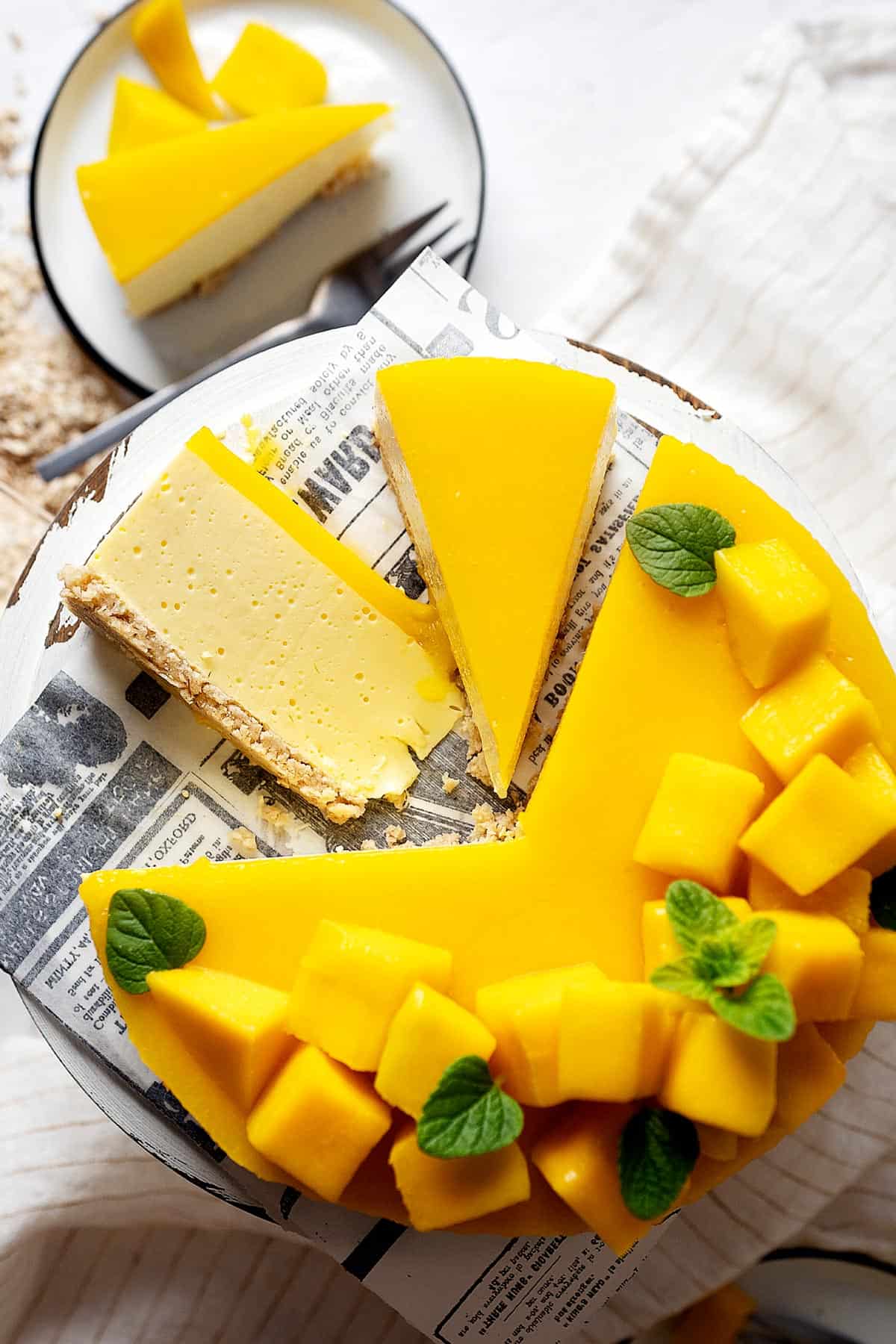 Slices of healthy no bake mango cheesecake on a cake stand together with the rest of it