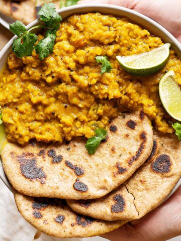 Holding a plate of lentils turmeric curry