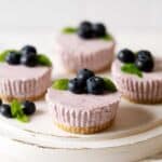 mini blueberry cheesecakes on a cake stand.