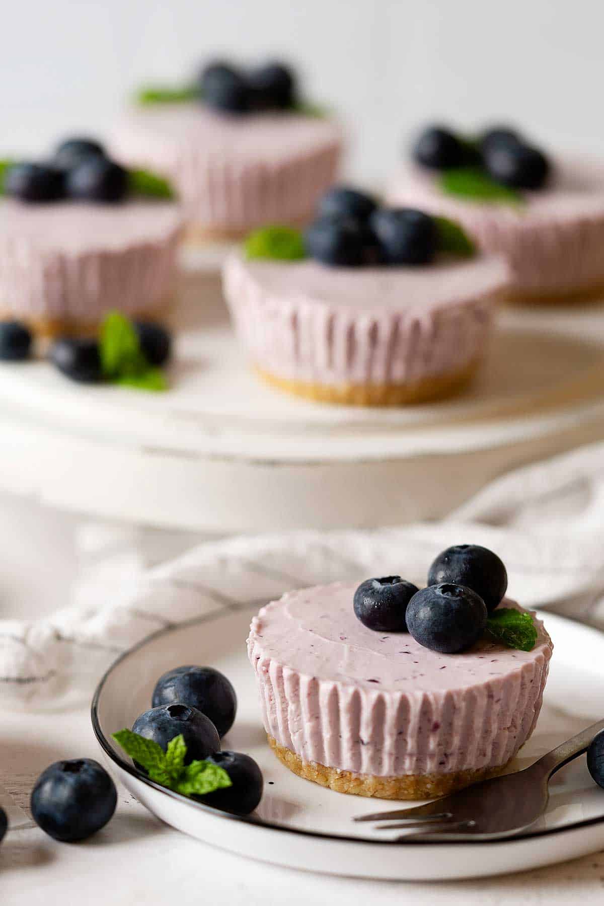 mini blueberry cheesecakes on a stand and plate.