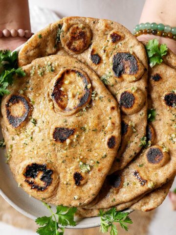 Holding a plate of whole wheat garlic naan