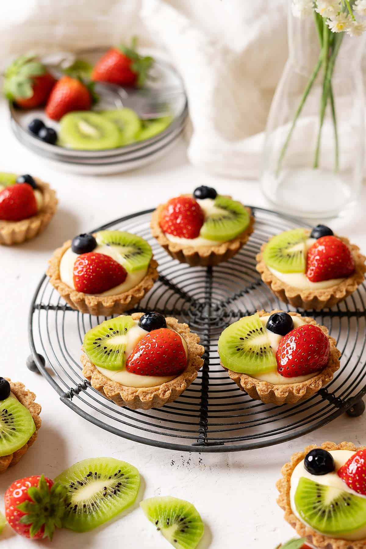 Healthier fruit tarts on a rack with fruits in the background view from front