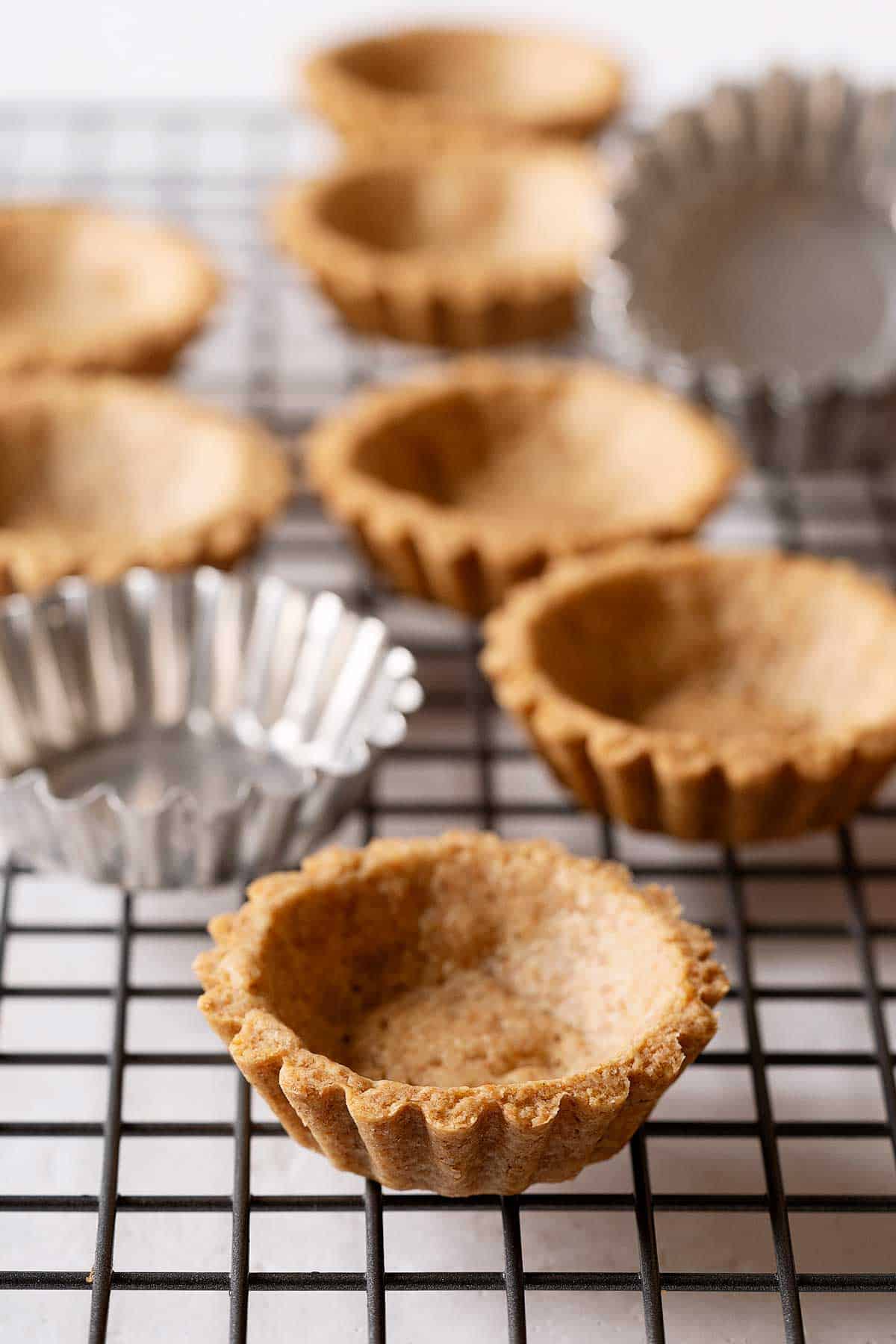 spelt tart shells on a cooling rack.