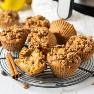 A rack of air fryer apple crumble muffins with one half eaten