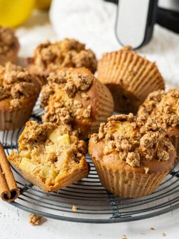 A rack of air fryer apple crumble muffins with one half eaten