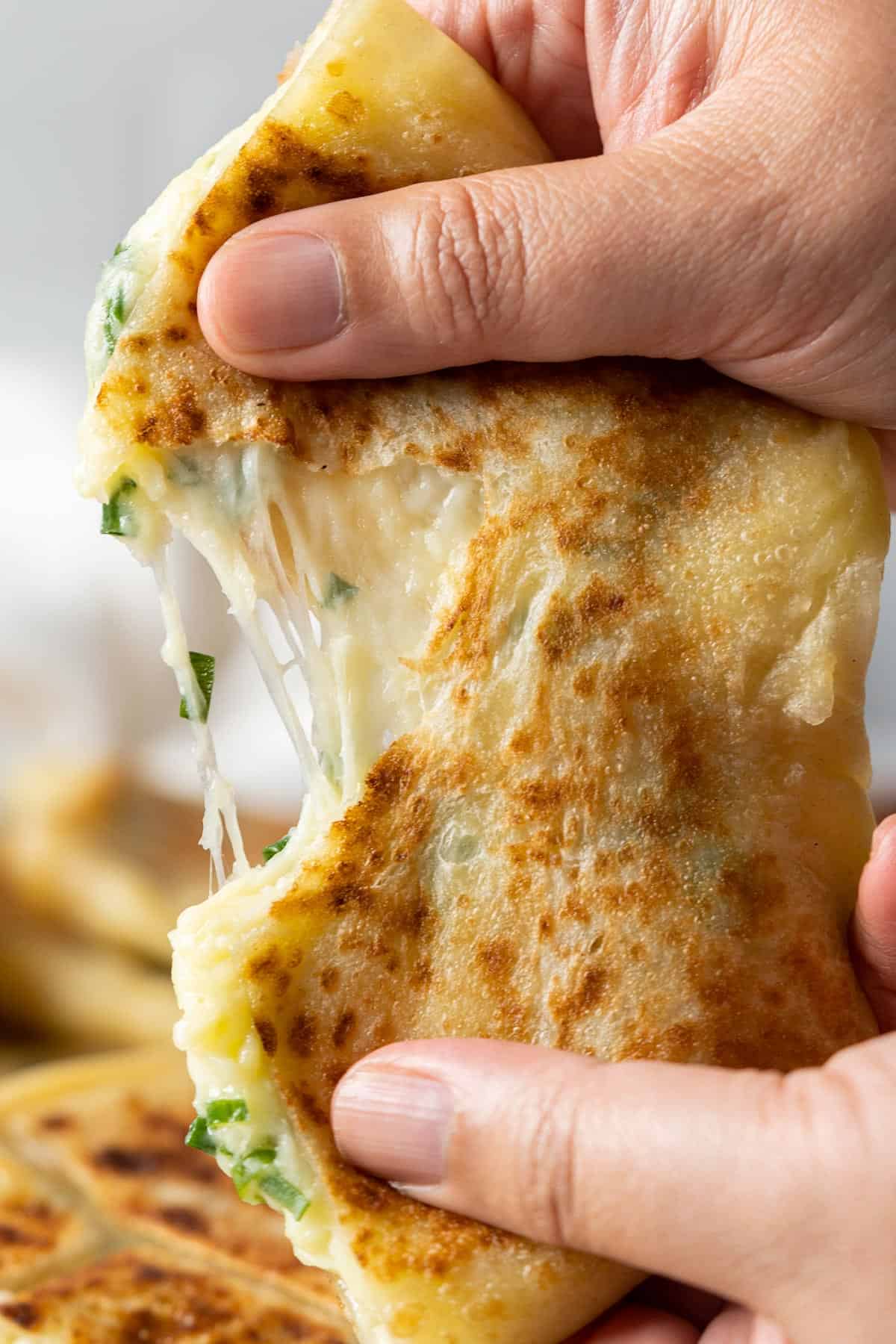 Tearing up a piece of cheese roti canai close up view