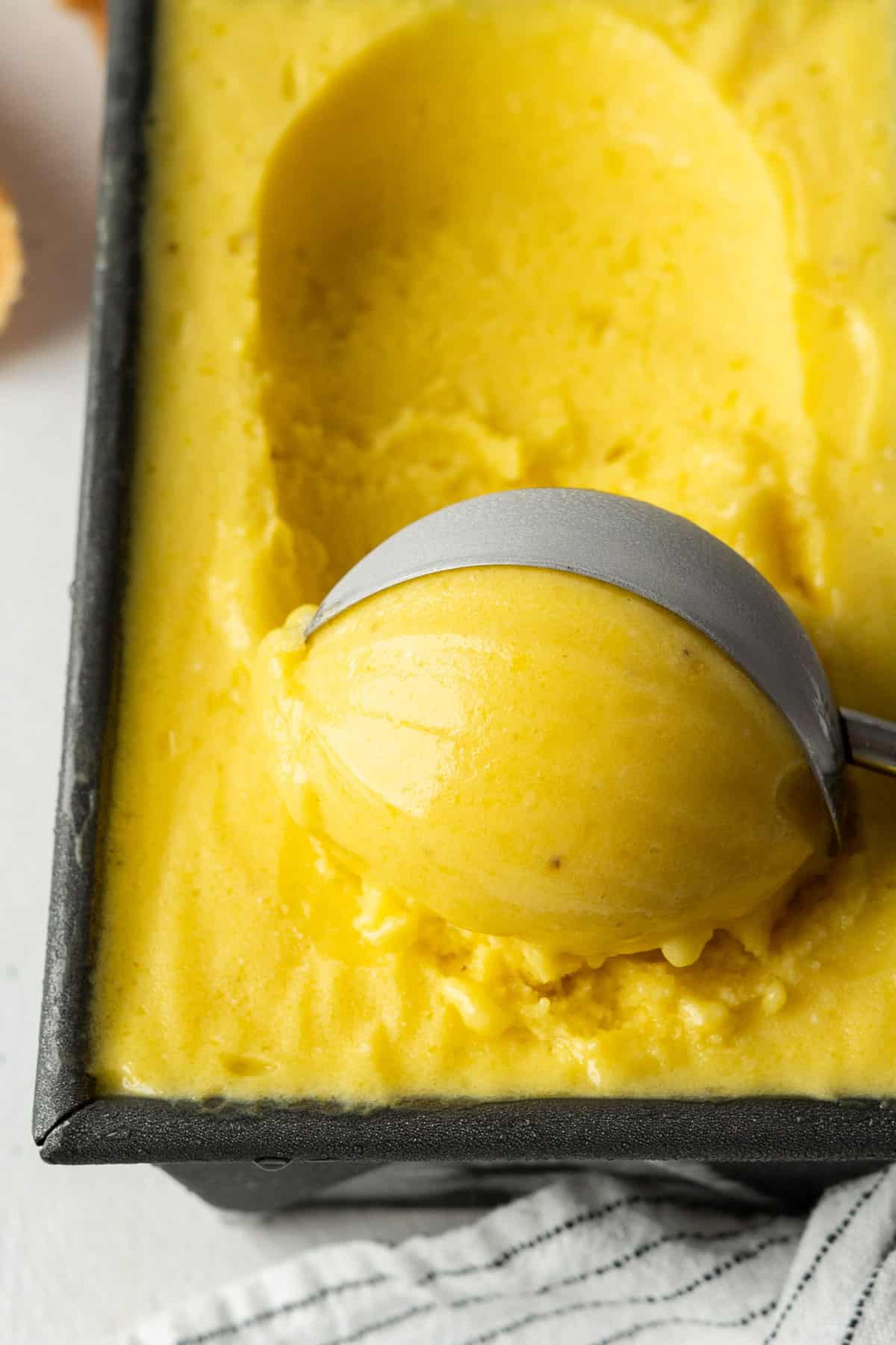 Scooping healthy no-churn mango ice cream.