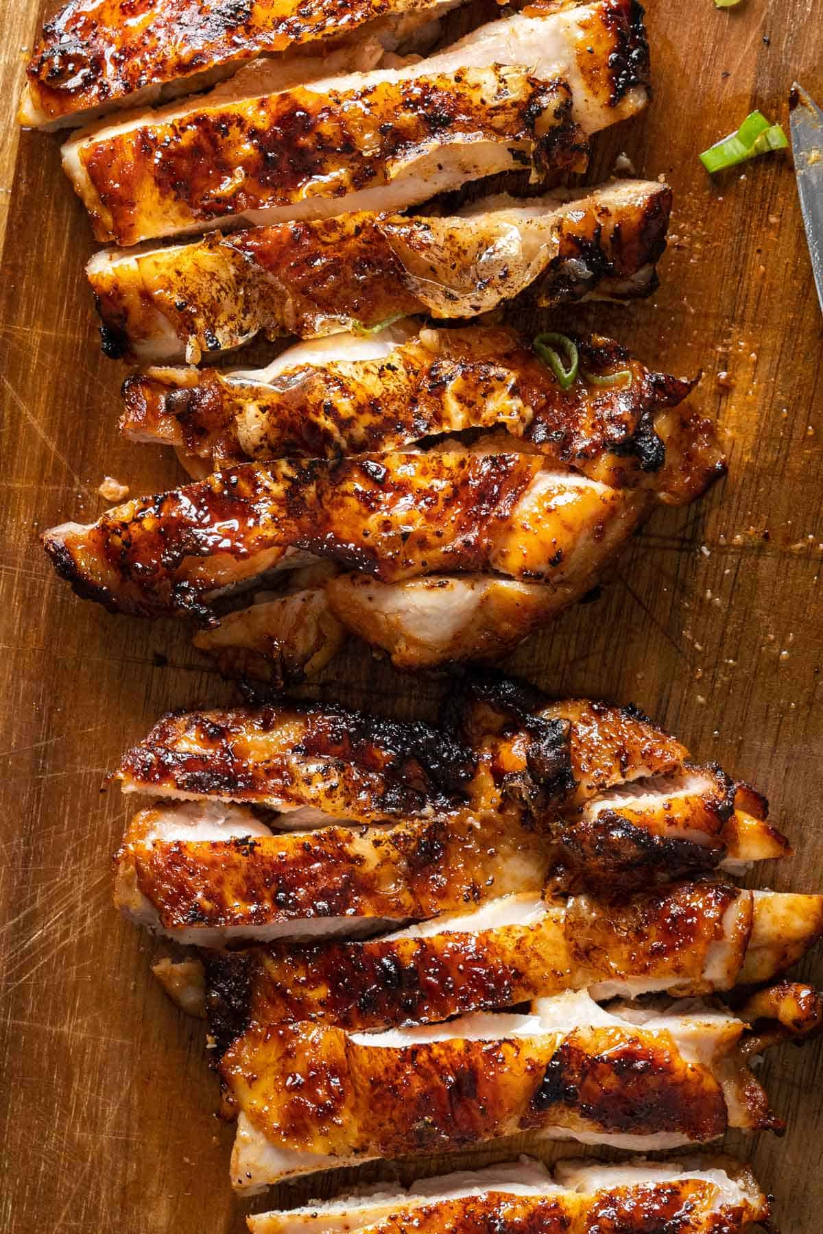 Close up of sliced air-fryer soy sauce chicken on a wooden board.