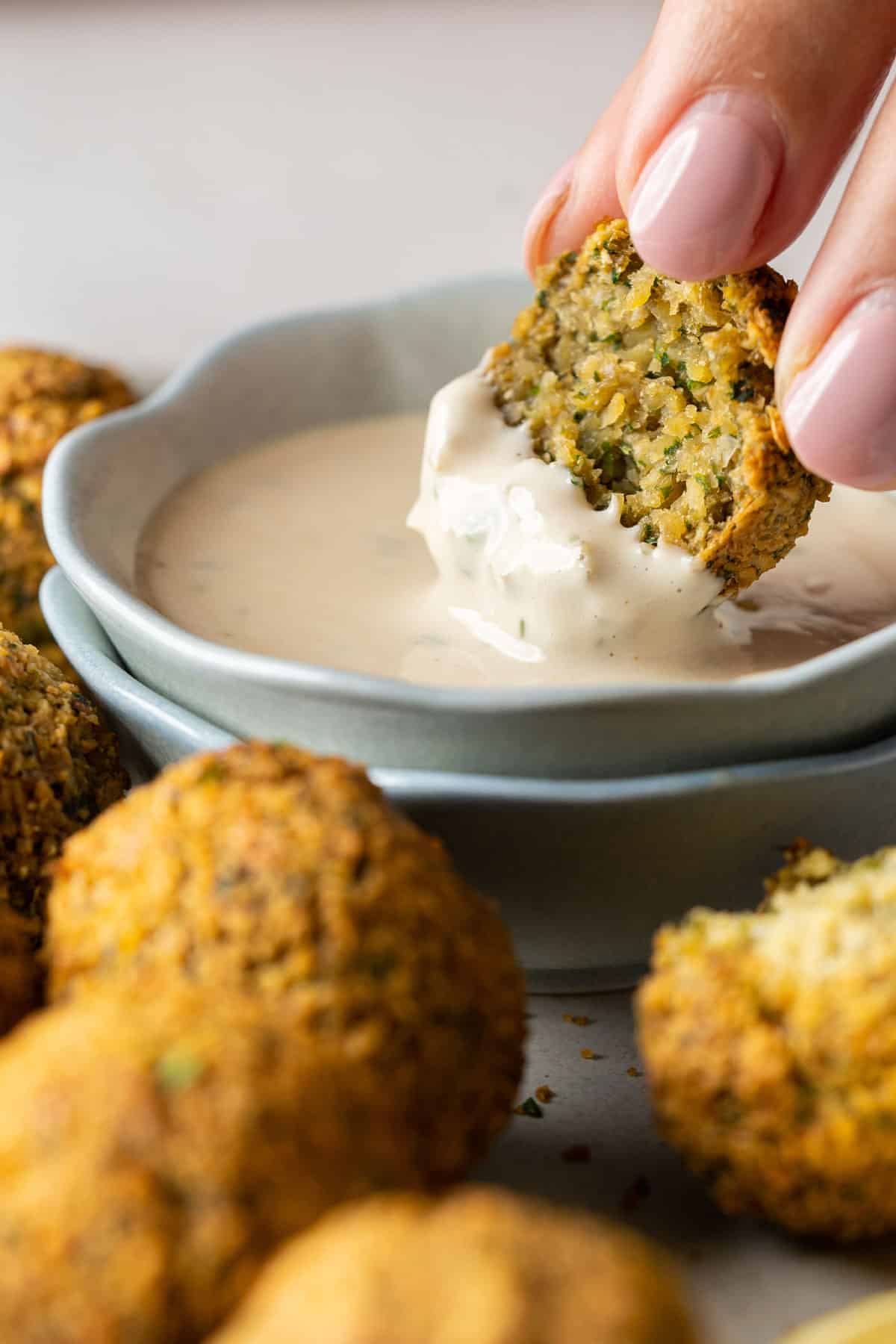 Dipping a falafel into tahini sauce.