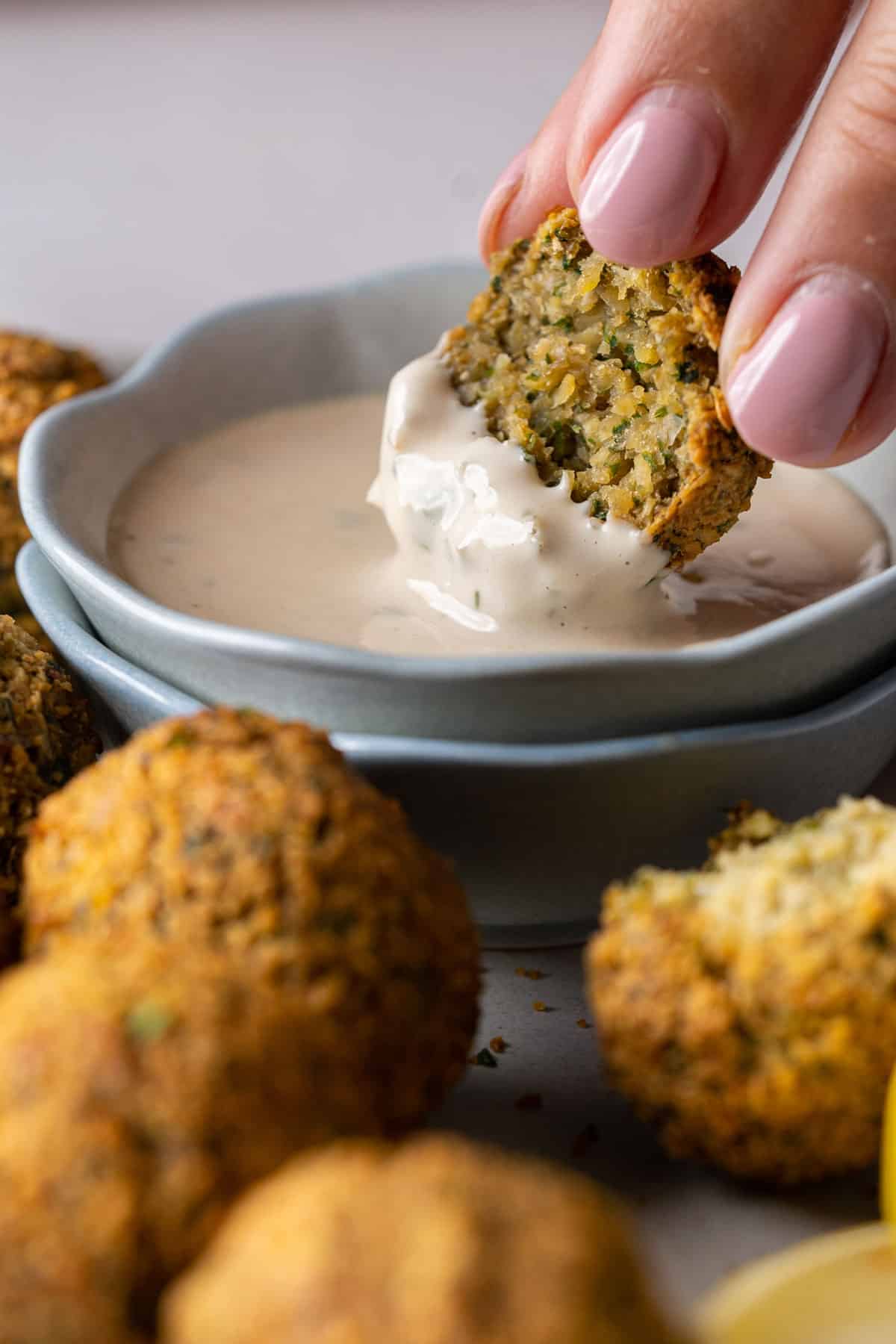 Dipping a falafel in tahini sauce.