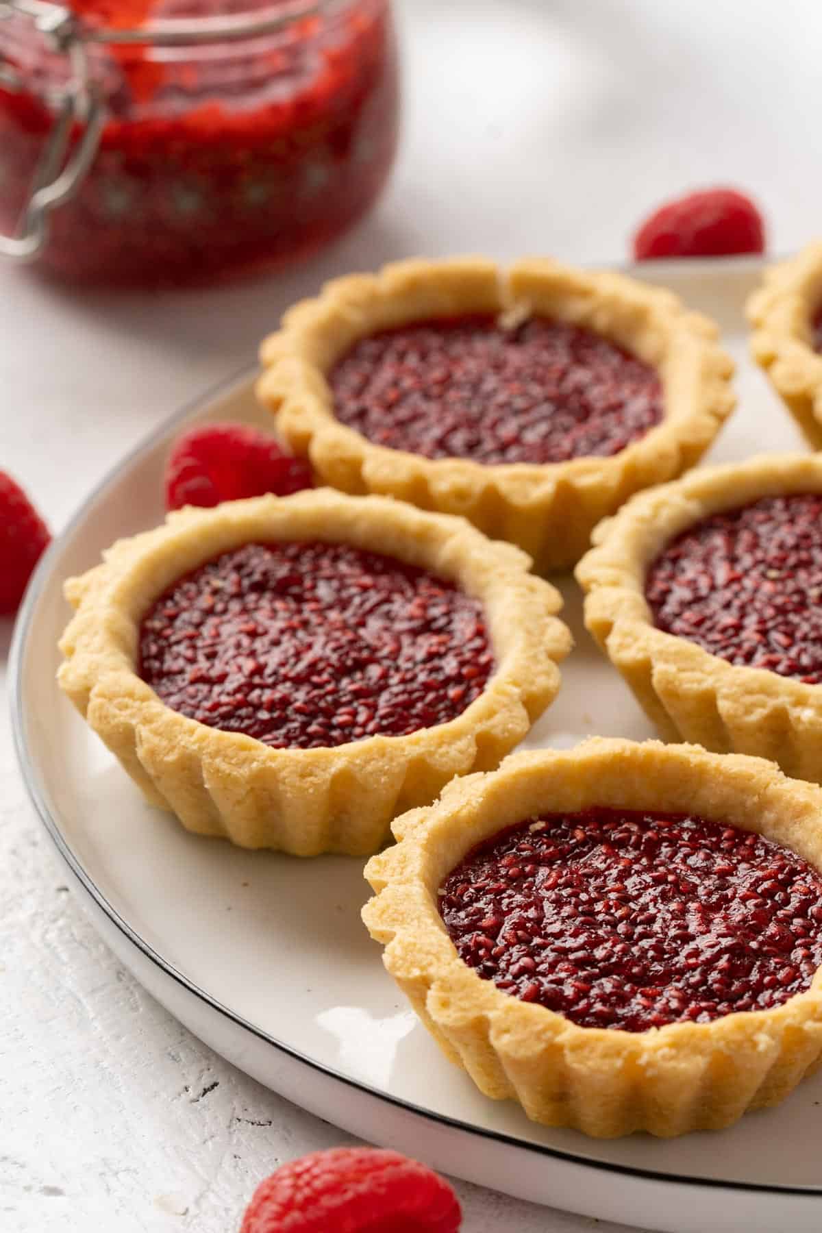 Some raspberry jam tarts on a plate.