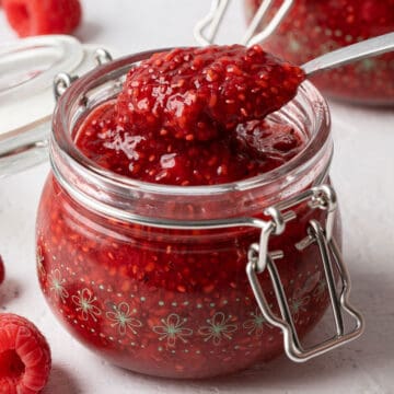 Spooning raspberry chia seed jam from a jar.