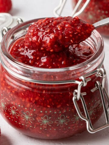 Spooning raspberry chia seed jam from a jar.