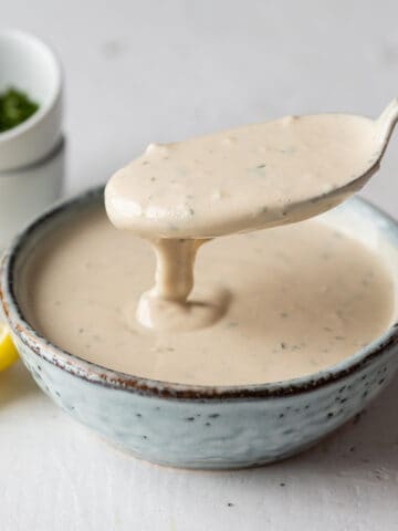 Spooning tahini sauce from a bowl.