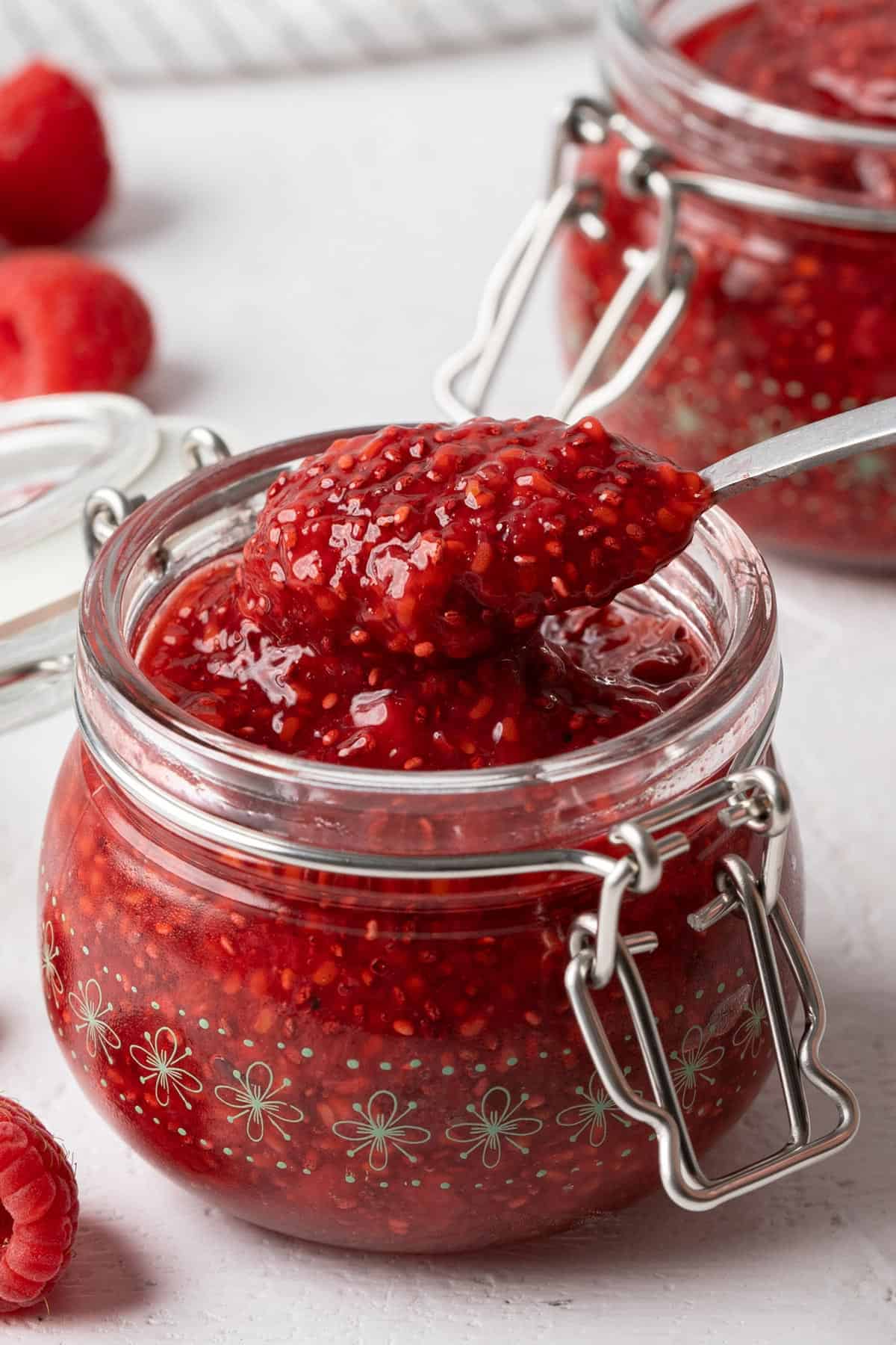 Spooning raspberry chia seed jam from a jar.