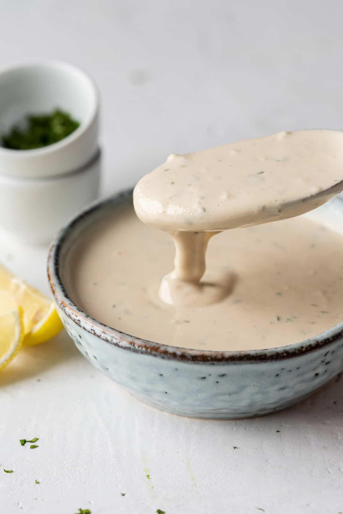 Spooning tahini sauce from a bowl.