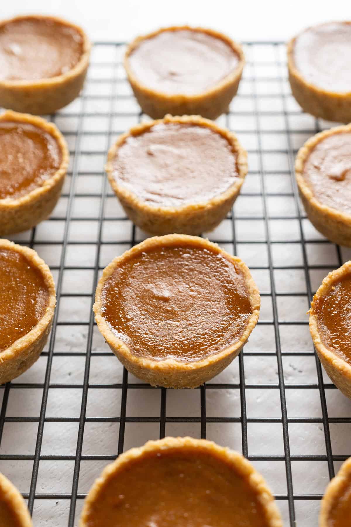 Baked healthy mini pumpkin pies on a cooling rack.