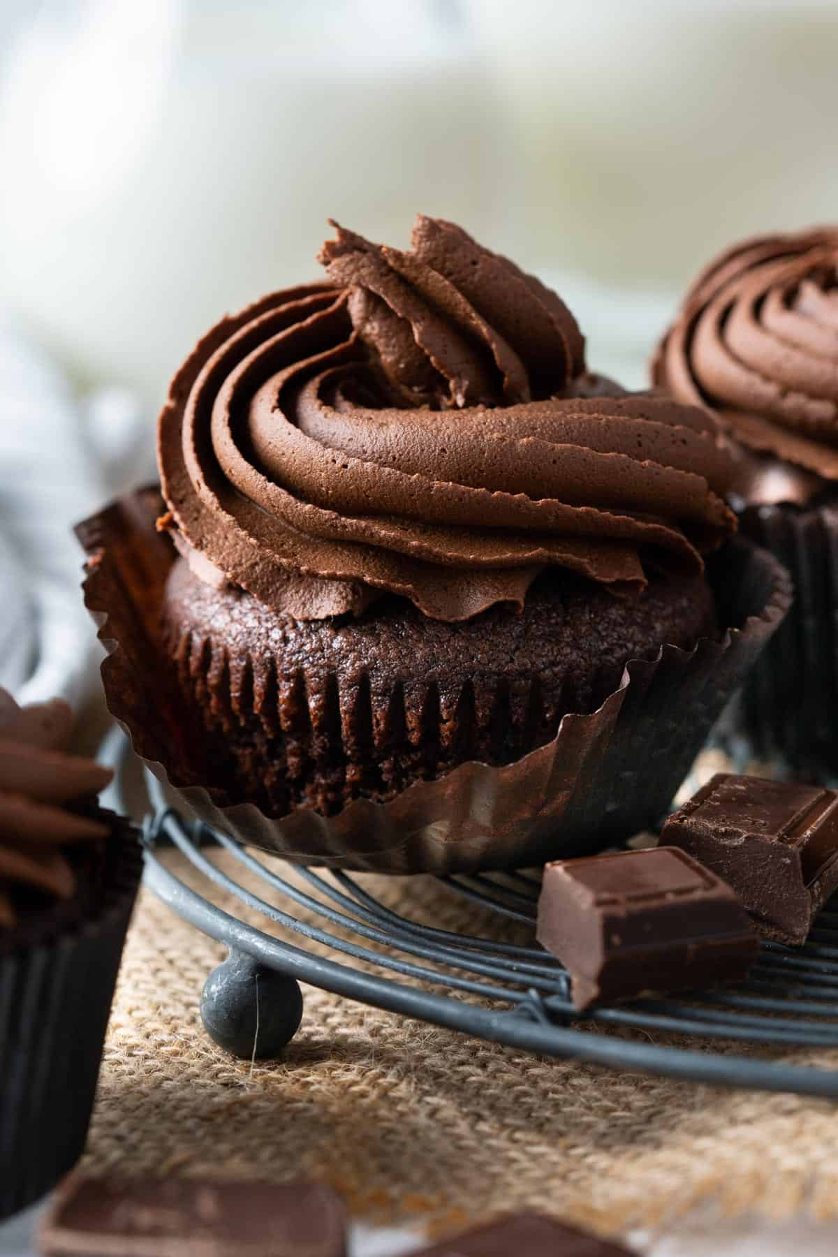 Close up of a peeled chocolate cupcake with frosting.