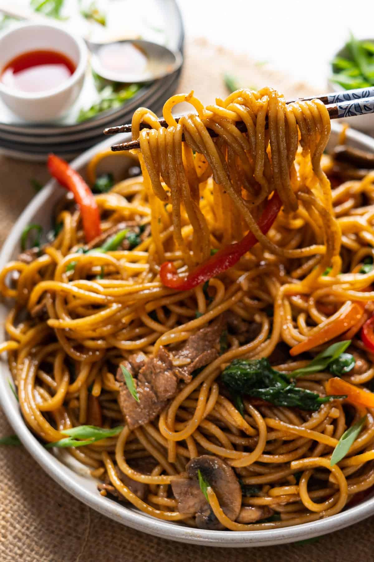 Lifting up some noodles from a plate using chopsticks.