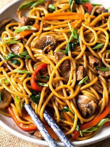 Lo mein noodles served in a plate with chopsticks.